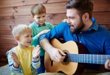 Man speelt gitaar en kinderen klappen met hun handen.
