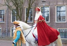 Sinterklaas bij de intocht op zijn paard Ozosnel met een Piet die het paard vasthoudt.