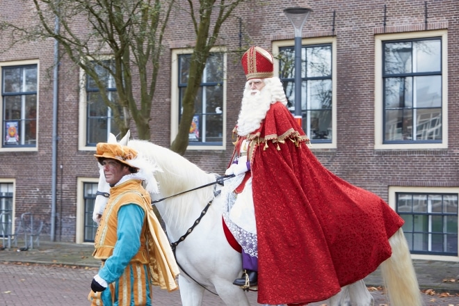Sinterklaas bij de intocht op zijn paard Ozosnel met een Piet die het paard vasthoudt.