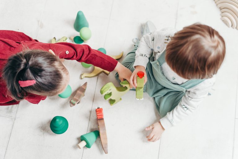 Twee kinderen spelen samen met houten speelgoed.