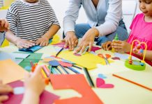 Kinderen op een kinderopvang knutselen met een pedagogisch medewerker.