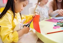 Meisje knipt gekleurd papier met een schaar op de kinderopvang.