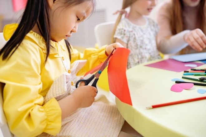 Meisje knipt gekleurd papier met een schaar op de kinderopvang.