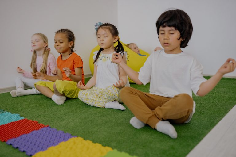 Kinderen zitten op de grond in yogaposes.