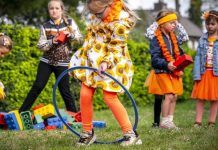 Meisjes spelen op koningsdag in oranje kleding met een hoepel en blokken