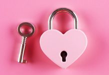 Hartvormig slot met sleutel bij een roze achtergrond