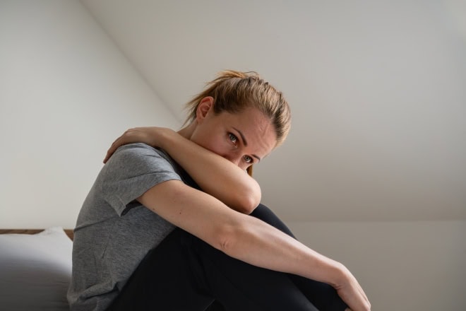 Vrouw maakt zich zorgen, heeft arm voor gezicht.