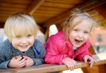 Happy kids having fun on outdoor playground. Spring/summer/autumn active sport leisure for children. Portrait of little boy and girl playing on kindergarten backyard
