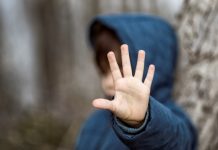 Kind geeft grens aan, steekt met hand stopteken voor gezicht
