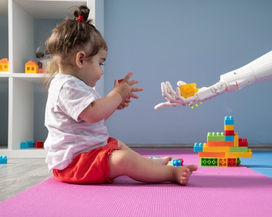 Baby girl playing with multi colored toy blocks while she is trying to grab a piece of blocks from humanoid robotic hand. She is sitting on the floor. Shot indoor with a full frame mirrorless digital camera.