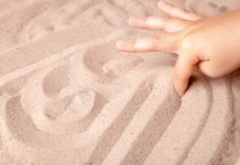 Kind schrijft met vinger in het zand.