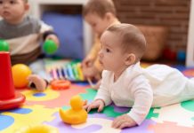 baby ligt op kleed en kijkt omhoog.
