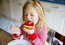 peuter, meisje eet boterham met aardbeienjam