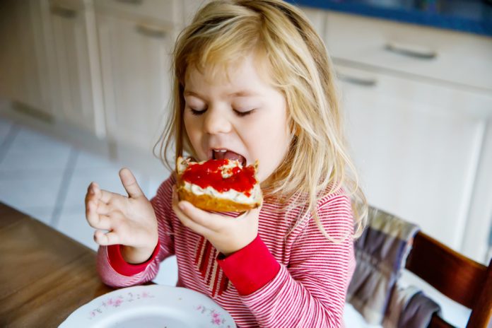 peuter, meisje eet boterham met aardbeienjam