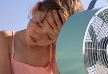 Kind zit voor ventilator met hand op hoofd, heeft het heet