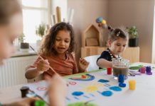 Happy little girls painting picture during creative art and craft class at school.