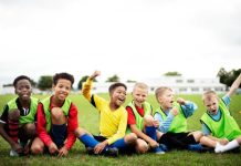 6 jongetjes op een rij zittend op het gras in voetbaltenue