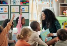 Reading, question and teacher with children in classroom for education, books and creative. Growth, kindergarten and academy with woman and kids at school for youth, hands raised or child development.