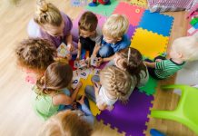 Kindernen bij een opvang spelen samen in een groepje, een kind valt erbuiten