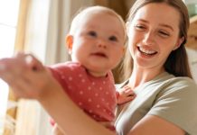 Young happy mother bonding to her cute baby child at home, playing at cozy room. Parenthood, love, care concept