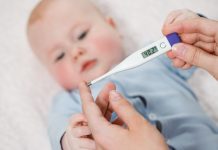 Snottebellenstress in de opvang: alles wat je wilt (of moet) weten over zieke kinderen Woman measuring temperature of small sick boy