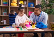 Vroege kinderopvang heeft langdurig positief effect op schoolprestaties in Noorwegen Mannelijke pedagogisch professional zit aan een tafel met jong meisje die speelt met speelgoed.