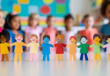 Rainbow colored paper human figures holding their hands on kindergarten or school background. Diversity and inclusion concept.