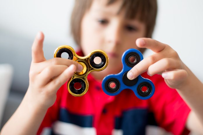 Little child, boy, playing with two fidget spinner toys Jongen speelt met fidget spinners