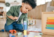 ‘Het kind is niet te complex, het systeem schiet tekort’ Jongen van peuterleeftijd op de peuteropvang, speelt met blokken.