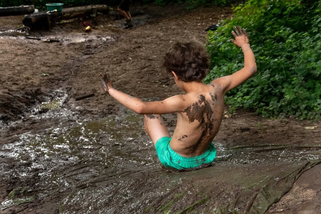 Modderdag (c) Sharallya Egger-2 Jongen in groene zwembroek glijdt van modderglijbaan af op modderdag