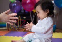 one years old baby girl clapping her hand with mom