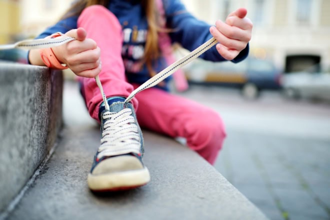 AdobeStock_129396070-2 Cute little girl learning to tie shoelaces outdoors on summer day