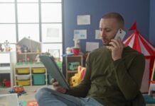Onderzoek naar schermgebruik in opvang: ‘Niet alles wat je met de ouderapp kan, moet je doen’ man tablet telefoon kinderopvang