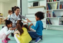 Laat de coronaperiode nog steeds sporen na in de kinderopvang? Teacher is playing with cheerful children at kindergarten