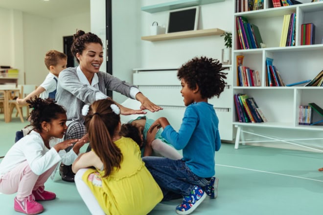 AdobeStock_293170223-2 Teacher is playing with cheerful children at kindergarten
