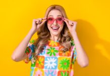 Blote schouders, navels of tenen op de groep: kan dat? Vrouw met zonnebril en vrolijk gekleurd truitje aan.