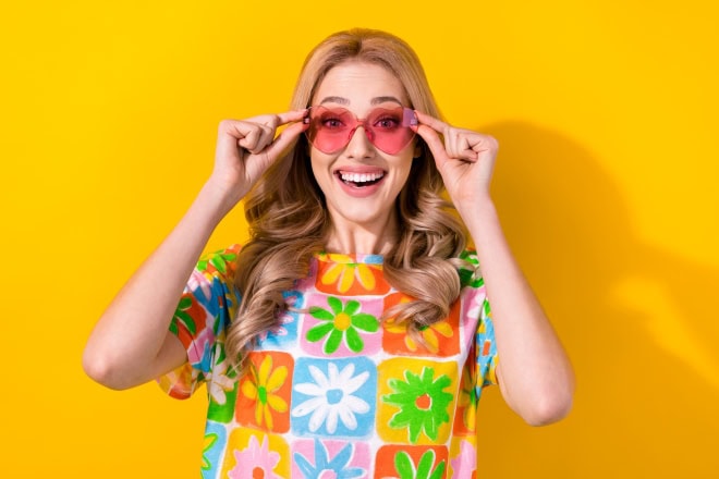 AdobeStock_615446775 kl Vrouw met zonnebril en vrolijk gekleurd truitje aan.