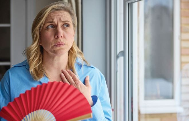 Nieuwe richtlijn Overgang en werk Vrouw met waaier, ze heeft het warm