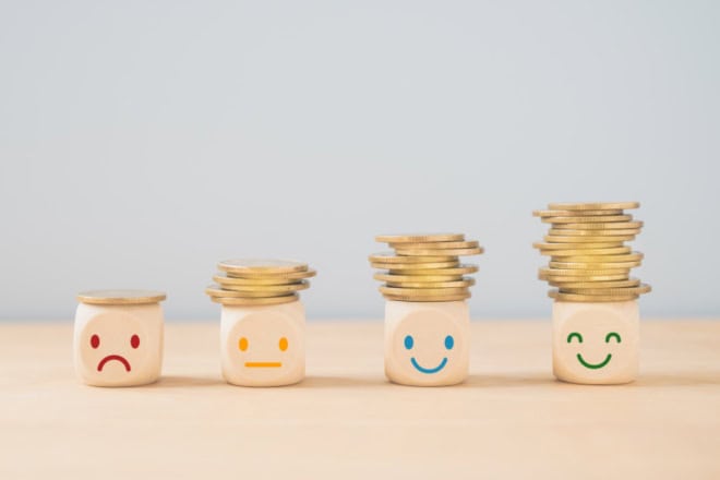 AdobeStock_450293156 (2)-2 Emotioneel gezicht op een stapel munten, geld besparen, sparen, welvaart, winst, geld voor een zorgbudget of verzekeringsconcept.
