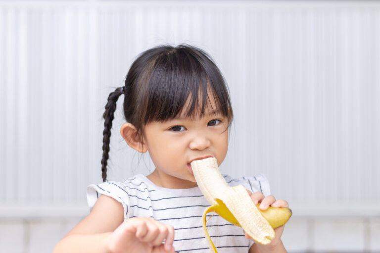 Het bananen-effect: waarom een kind op de opvang net iets meer kan en doet dan thuis Meisje met banaan